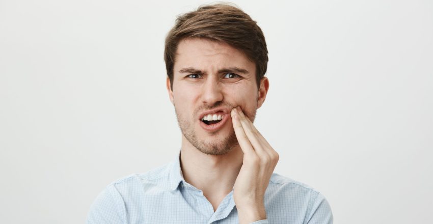 Na zdjęciu mężczyzna, któremu dokucza ząb zatrzymany.